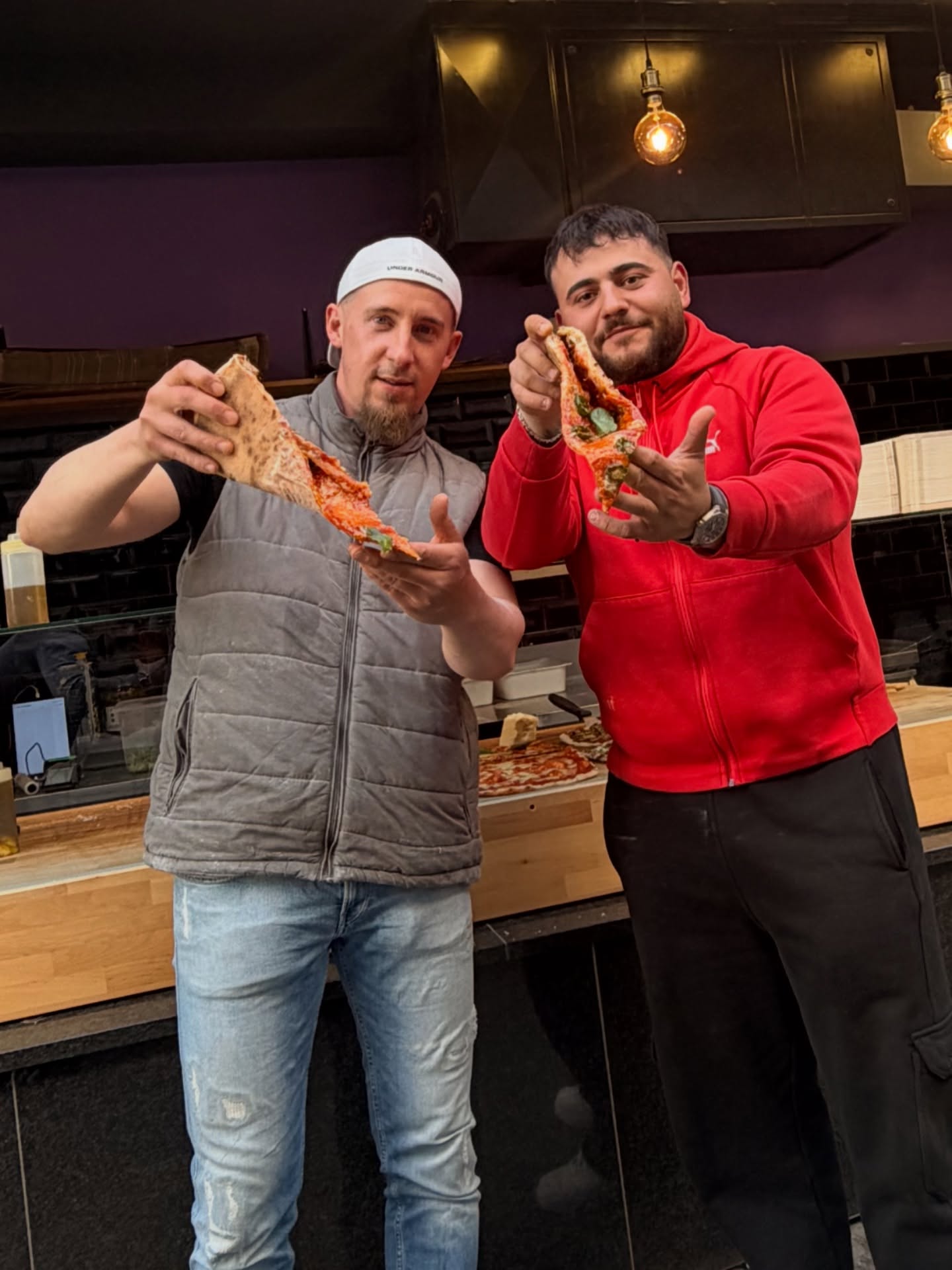 Henry und Kollege zeigen frische Pizzastücke