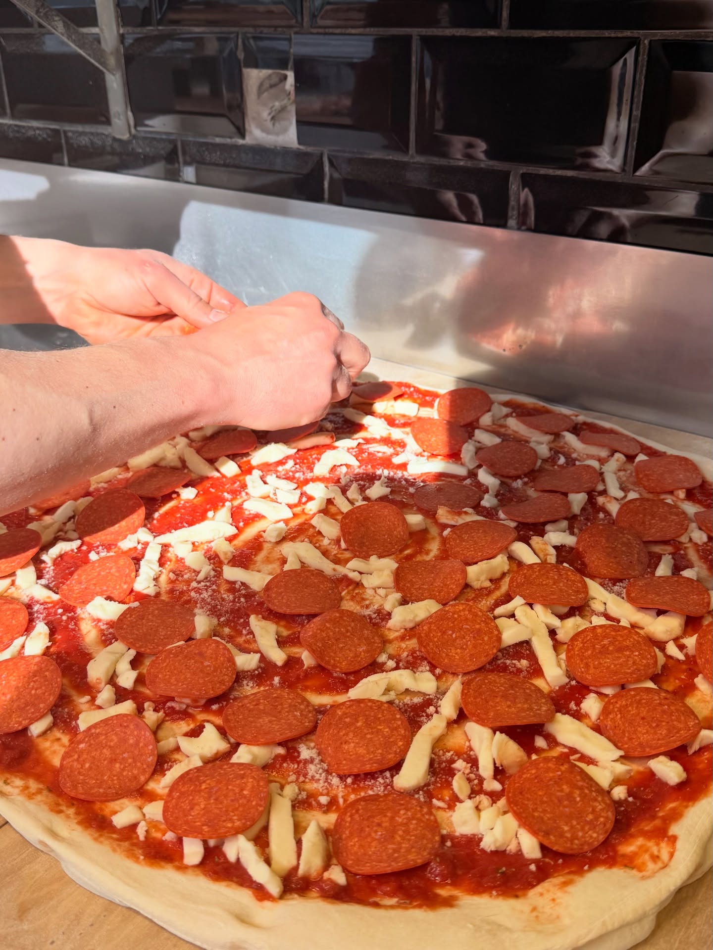 Meterpizza wird mit Pepperoni belegt